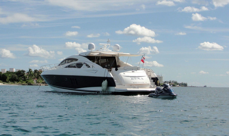 Stern view of the 72 ft Sunseeker Predator Aguila with jet ski alongside, anchored near the Cancun coastline