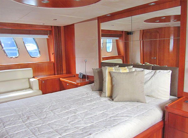 Master stateroom of the 72 ft Sunseeker yacht with queen bed, cherry wood paneling and portholes, Cancun charter