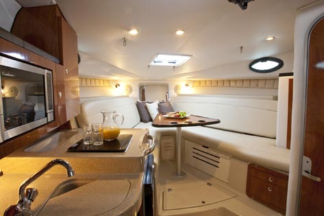 Interior cabin of 30 ft Wellcraft sport cruiser with kitchenette dining table and V-berth for overnight fishing charters