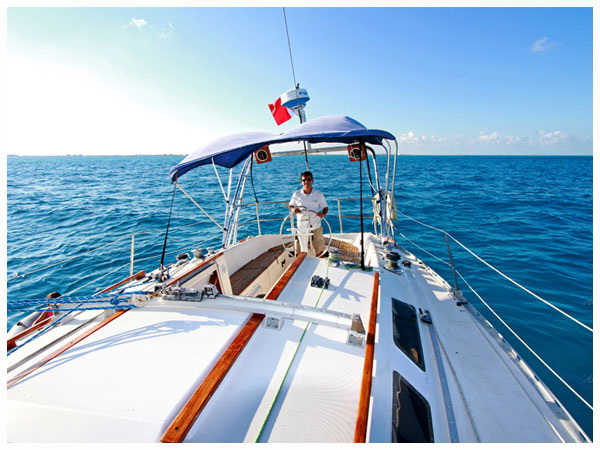Capitán al timón del velero de 42 pies navegando en el Mar Caribe abierto, alquiler de velero de lujo desde Cancún